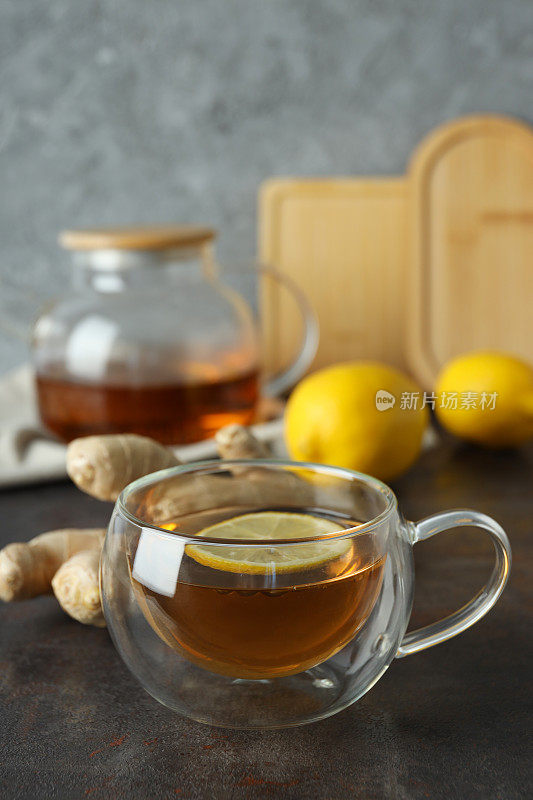 茶杯和茶壶与茶，柠檬和姜在灰色背景