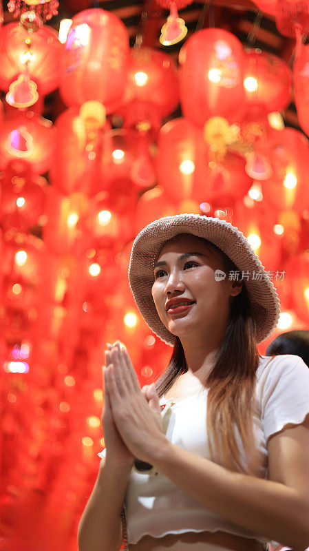 泰国唐人街街市(Yaowarat)，一名亚洲妇女在灯笼下祈福许愿。