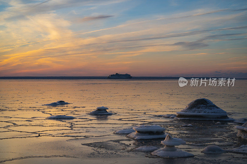 爱沙尼亚冬季日落时波罗的海的海景。一艘游船在结冰的海面上航行。