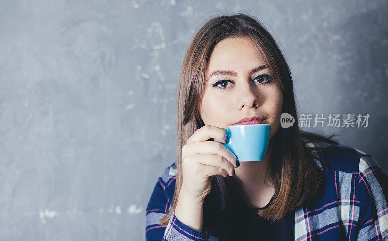 年轻的白人妇女捧着一杯咖啡享受在自由时间的肖像。