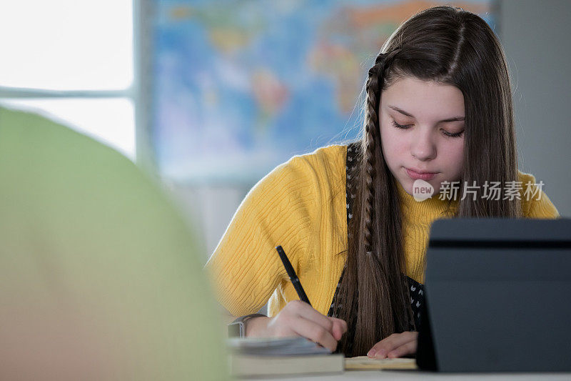 漂亮的初中女孩在课堂上考试时使用科技