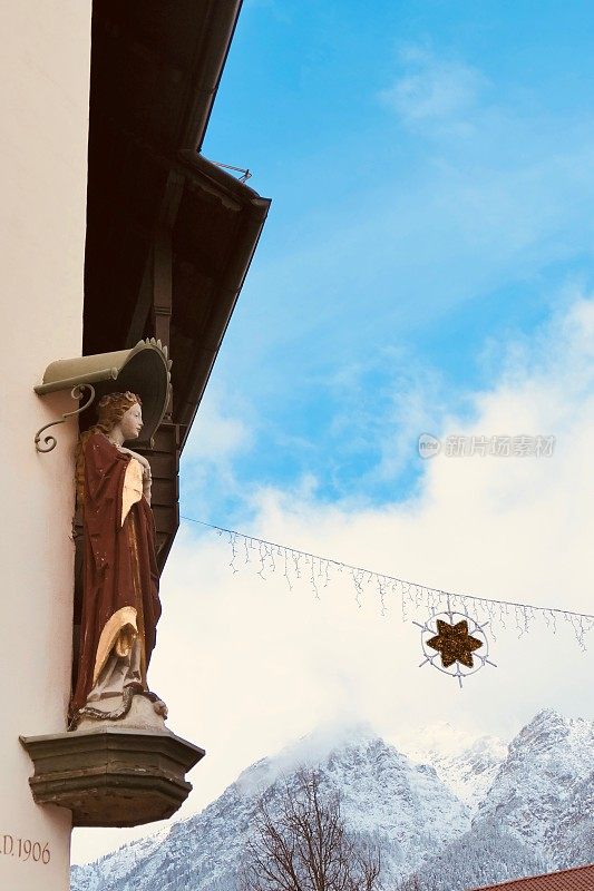 CC-加米施-帕滕基兴圣诞市场，巴伐利亚-房子上的女人雕像和天空中的星星雪花装饰