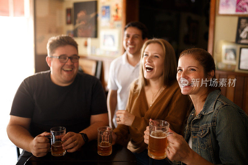 朋友们在电视上看体育节目，在酒吧里喝啤酒