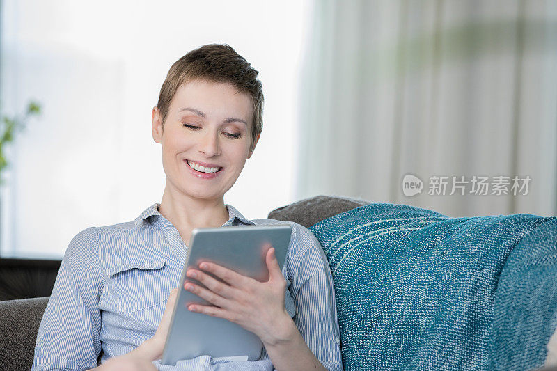快乐的女人用数码平板电脑上网或在家里网购