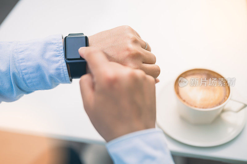 商人的手在咖啡馆使用智能手表，商务或通讯技术概念，镜头光晕效果。