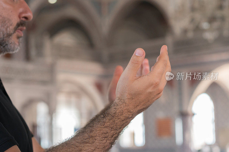 穆斯林男子的手与清真寺内部的背景祈祷