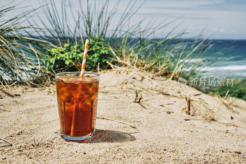 在一个炎热阳光明媚的夏日，在纽基菲斯特拉海滩的沙丘上喝一杯冰黑咖啡。