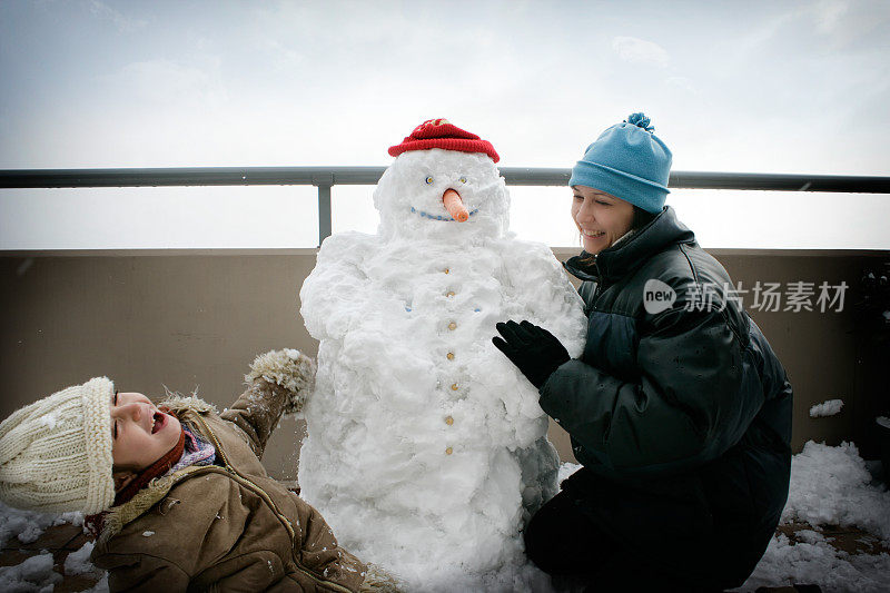 快乐的妈妈和女儿玩雪人的肖像