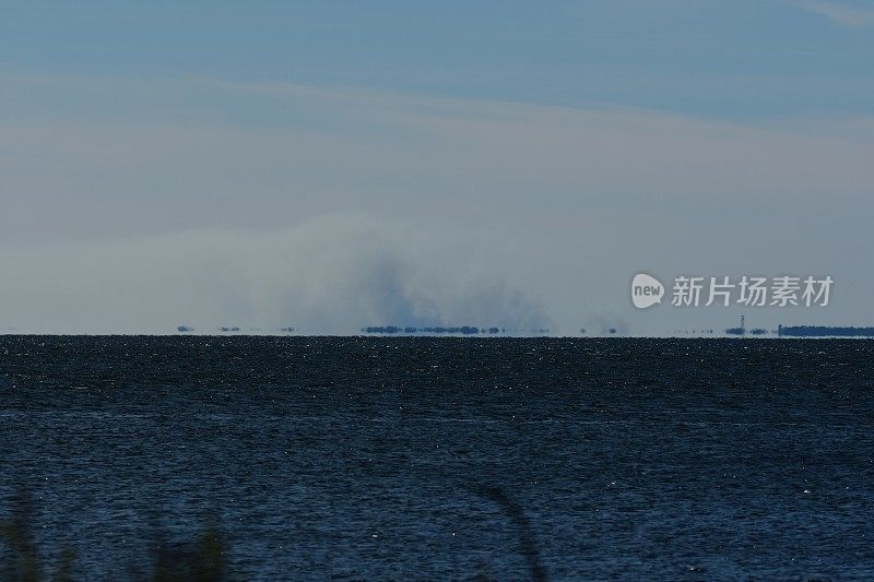 在遥远的海岸线上升起的烟雾是由指定的大火引起的