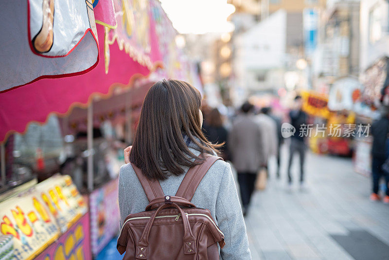 后视图的妇女走在街道上的旅游景点