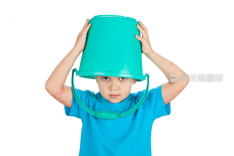 一个5岁的学龄前男孩把一个绿色的水桶戴在头上，孤立在白色的背景下