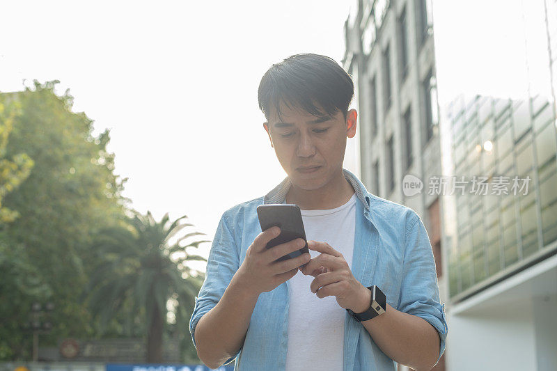 年轻的亚洲人在街上使用手机
