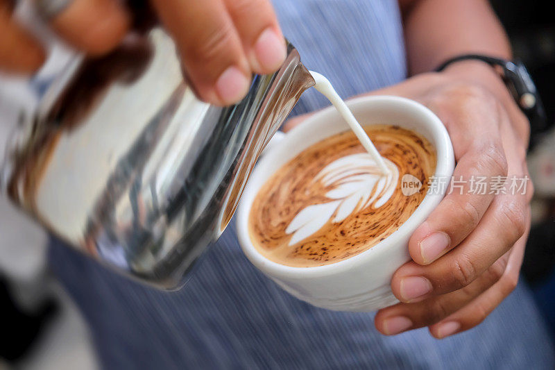 亚洲男咖啡师用蒸汽牛奶制作拉花艺术