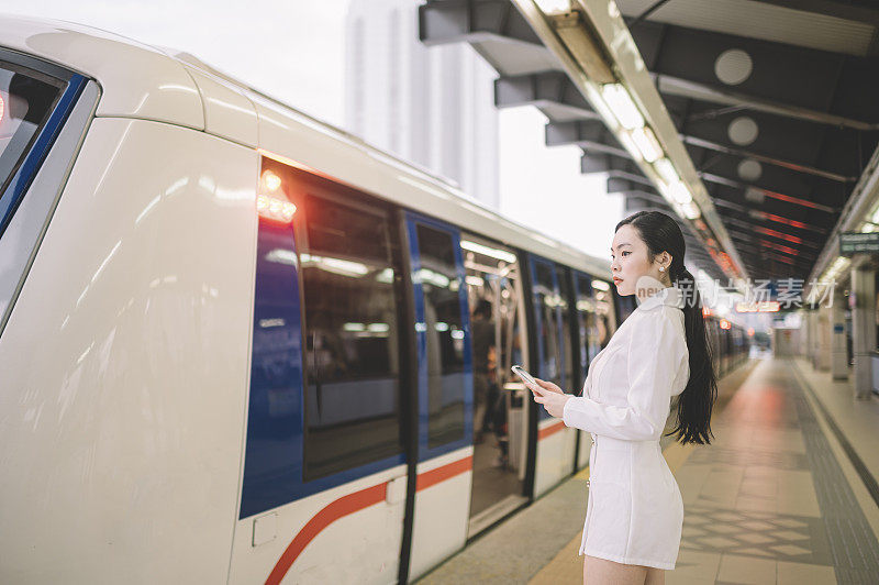 一位年轻的亚洲华裔女商人正在单轨火车站等待火车