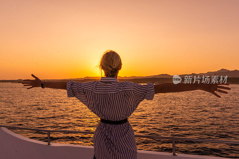 游艇上的女人望着夕阳。