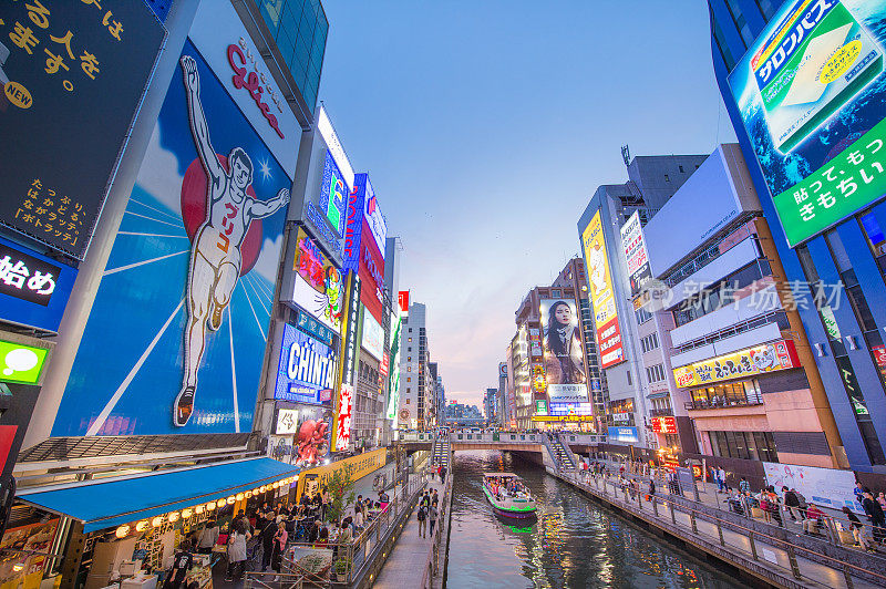 在日本大阪的道顿堀，五颜六色的广告牌照亮了大阪夜市周围的商店和零售店