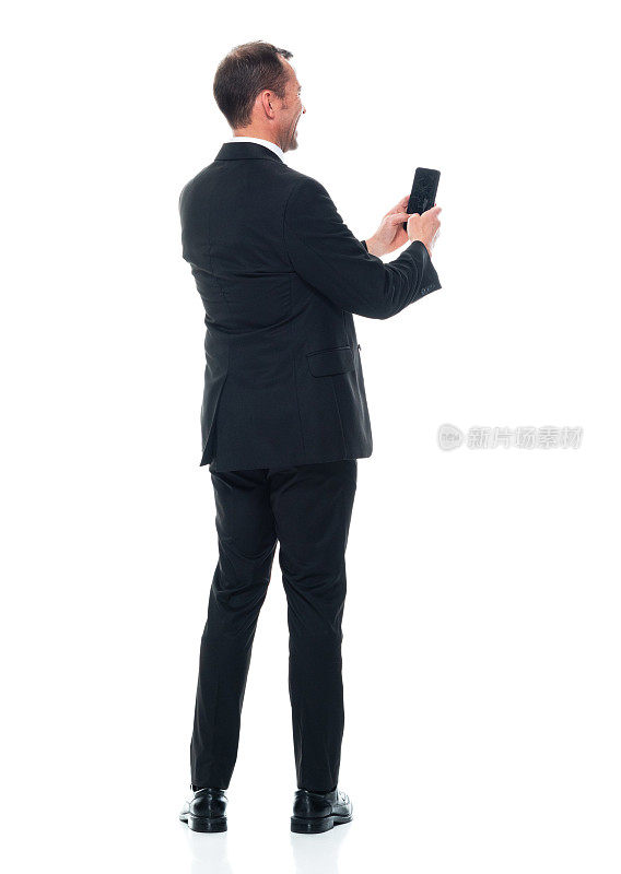 白人男性穿着商务装站在白色背景前使用智能手机