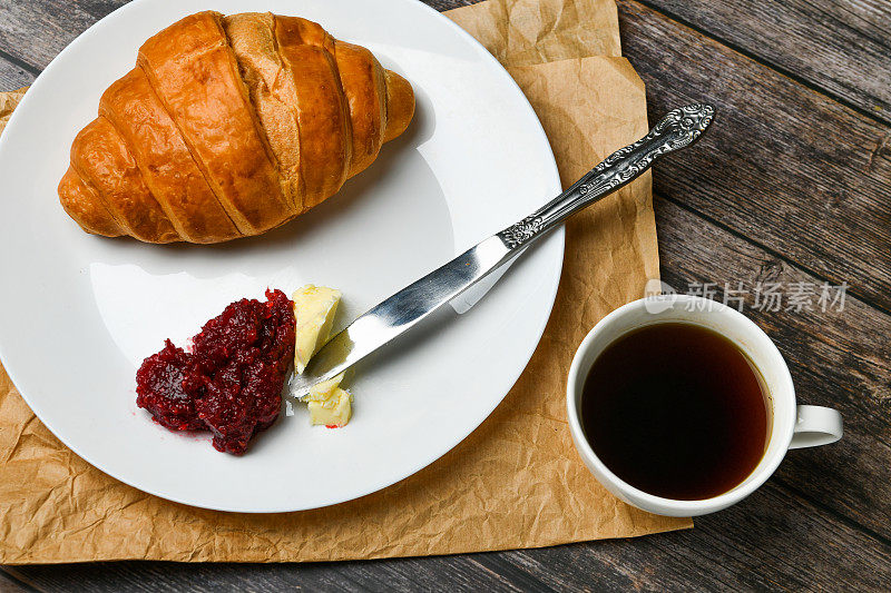 早餐,羊角面包。清晨的开始。新的法国羊角面包。木质背景上放着咖啡杯和新鲜烘焙的羊角面包。从以上观点。早餐有羊角面包和咖啡