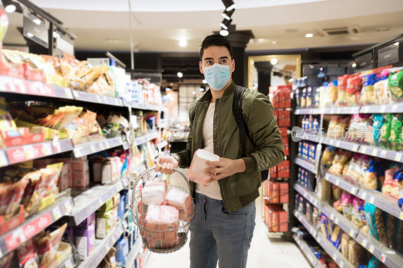 冠状病毒肺炎爆发期间，一名男子戴着一次性医用口罩在超市购物。疫情暴发时的防护和预防措施。