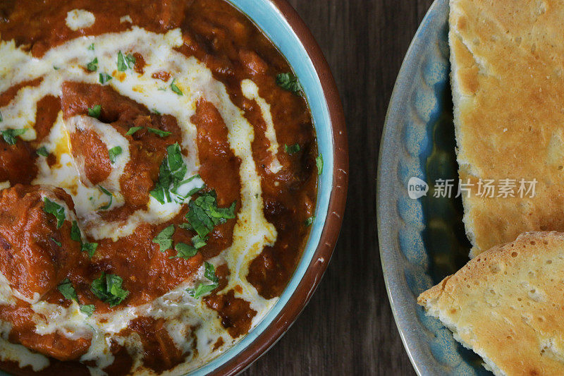 这是一碗自制的咖喱鸡，配上印度烤饼和raita(酸奶酱)的特写画面