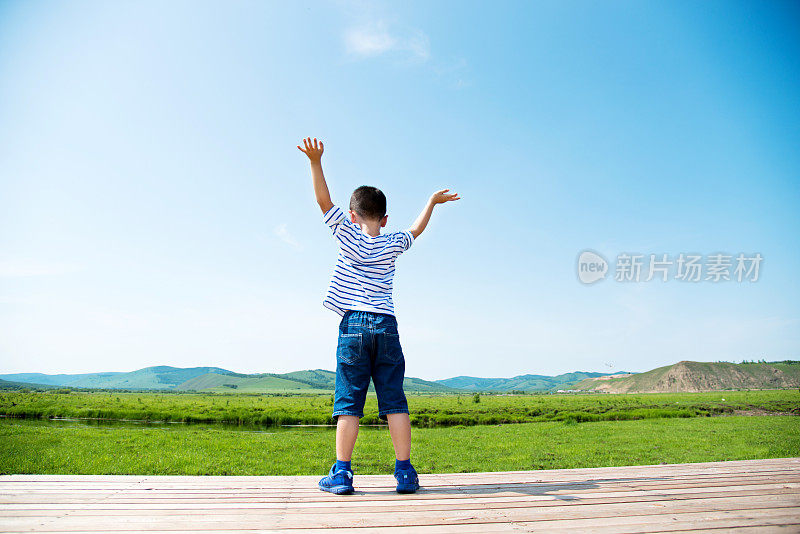 小男孩双手高举在户外