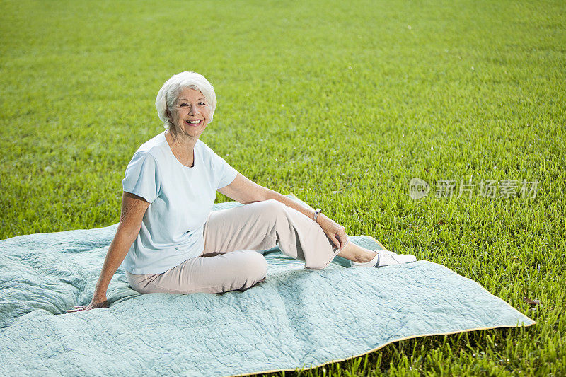 坐在野餐毯子上的老妇人