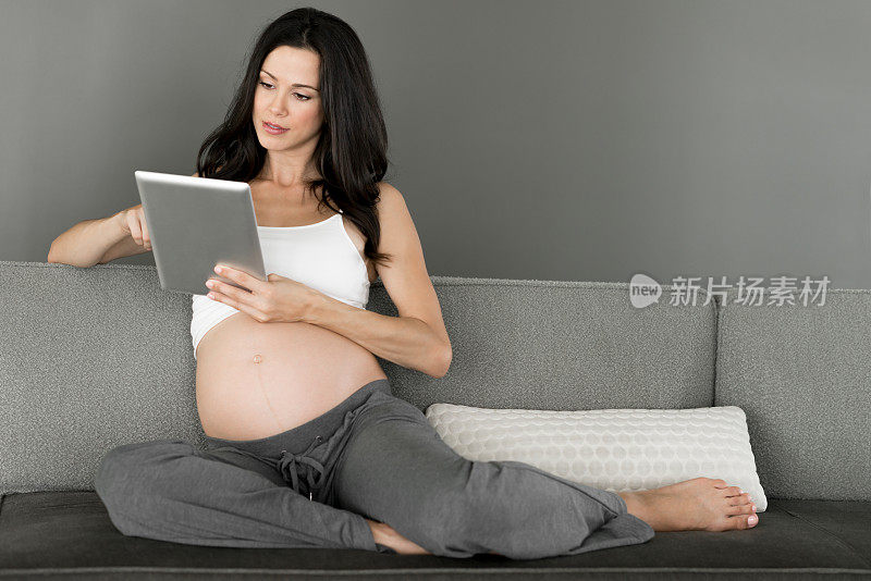 年轻孕妇手持数码平板电脑