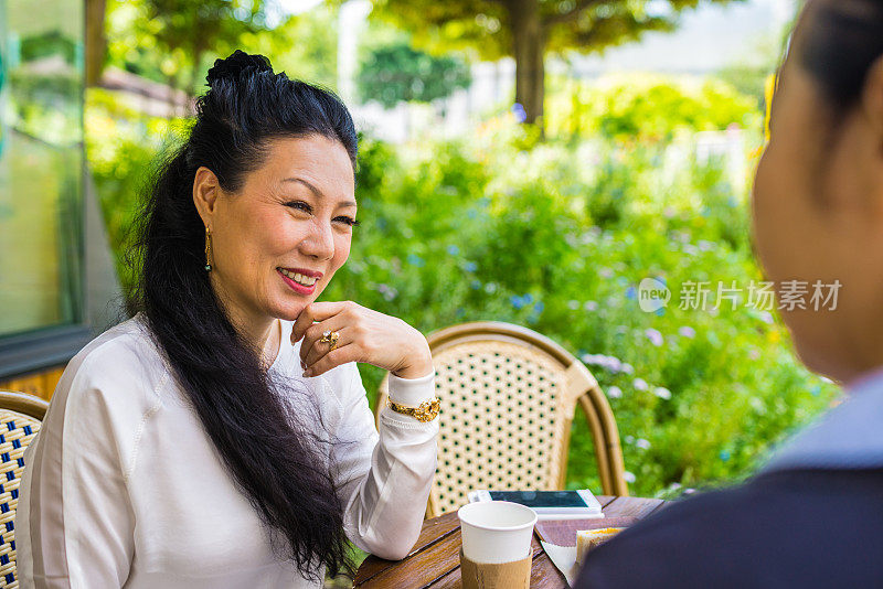 快乐的日本老年妇女在花园里享受咖啡