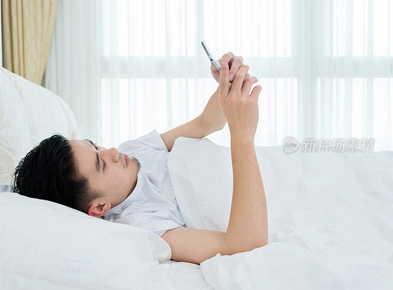年轻人在床上使用智能手机