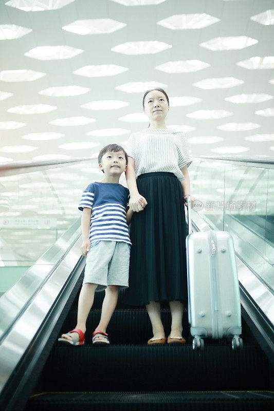 一个女人带着她的孩子经过机场航站楼