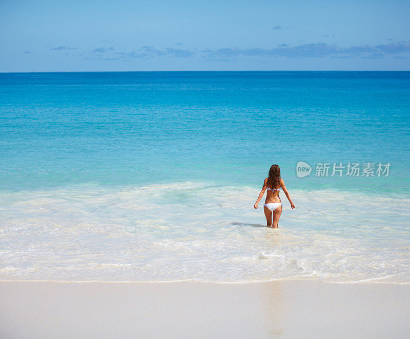 女人在海滩上放松，张开双臂享受自由