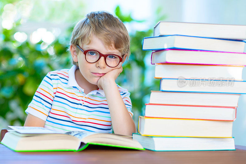 沮丧的小男孩戴着眼镜和书