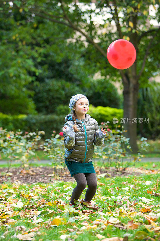 小女孩在公园里玩接球和红色的足球