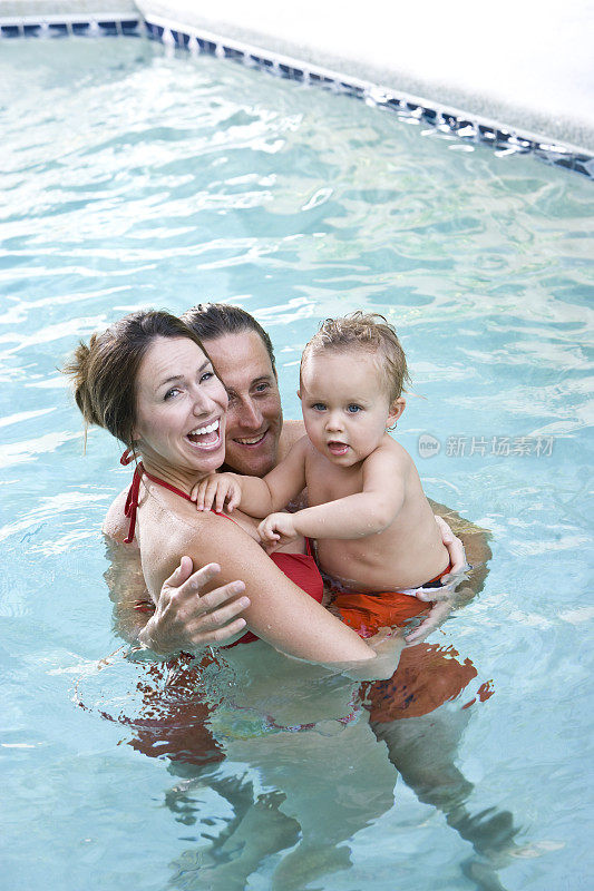 快乐的家庭和小男孩在游泳池里玩
