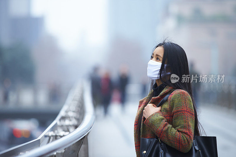 戴着面具的年轻女子在雾霾的城市里