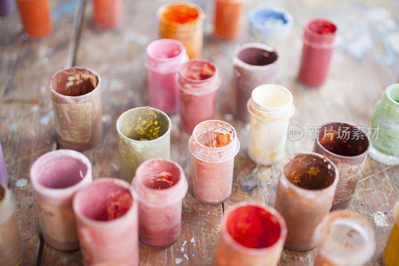 桌子上的罐子里装着不同颜色的油画