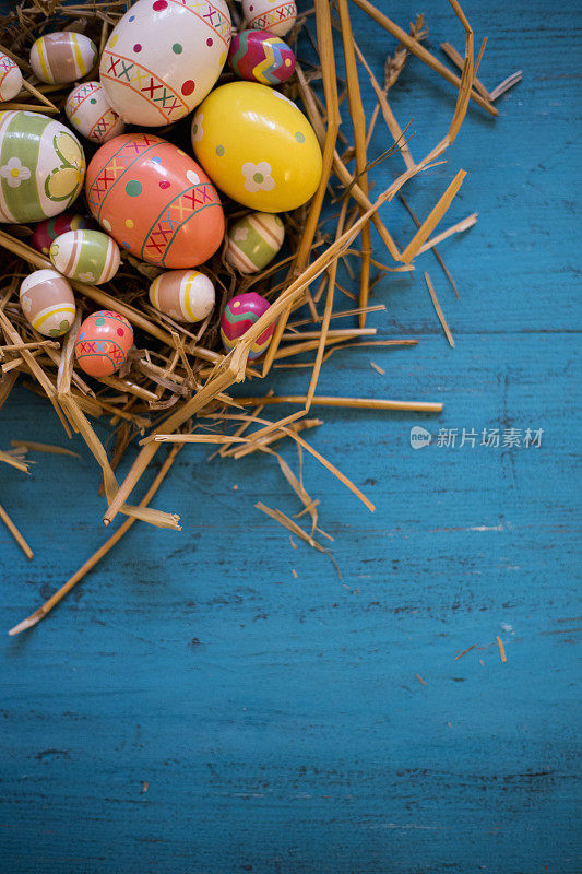 五颜六色的复活节彩蛋放在一张木桌上的稻草窝里