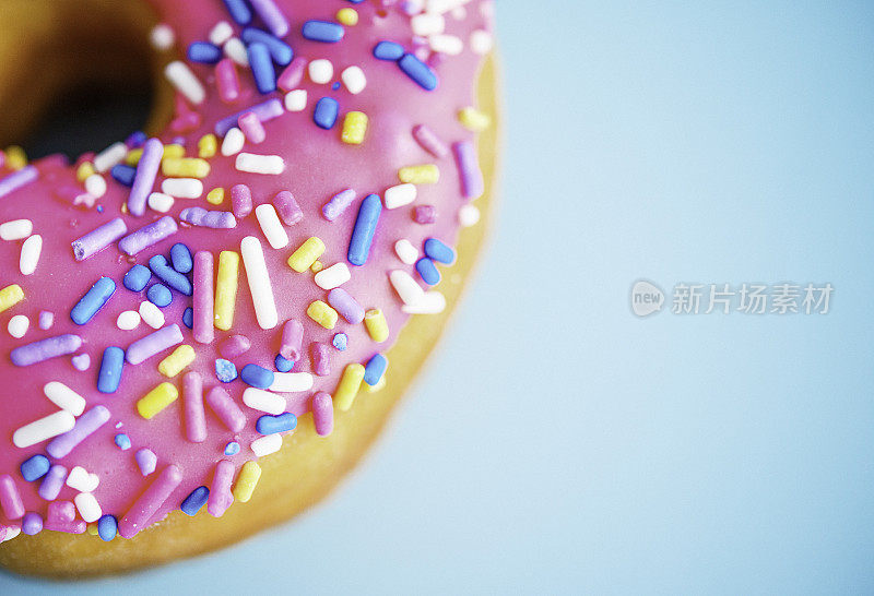 蓝色背景上有粉色糖霜和糖屑的甜甜圈