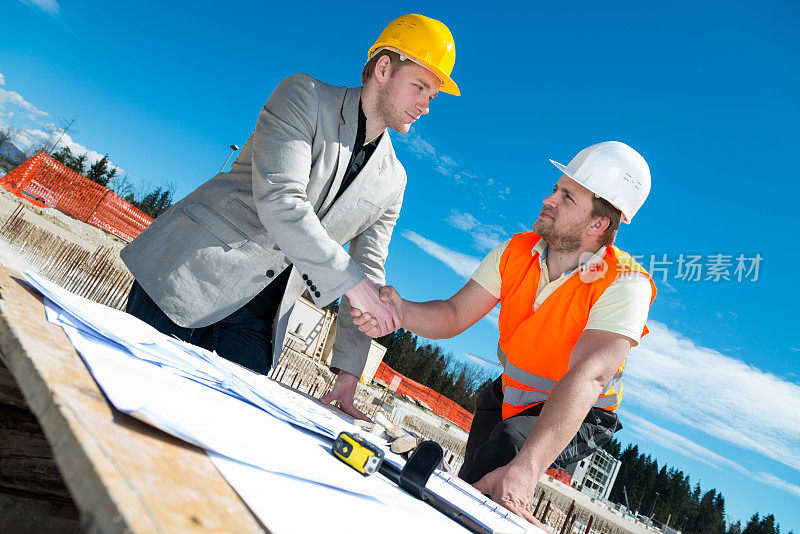 建筑师和建筑工人握手。