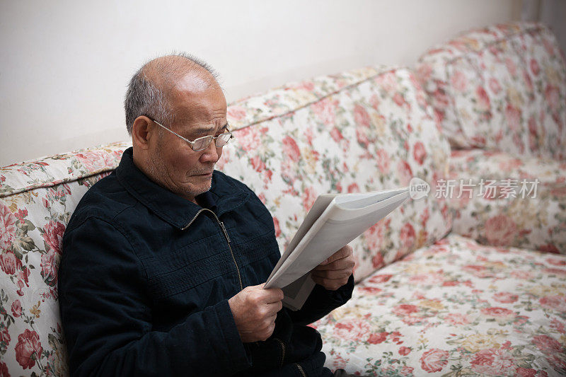 一位亚洲老人在看报纸