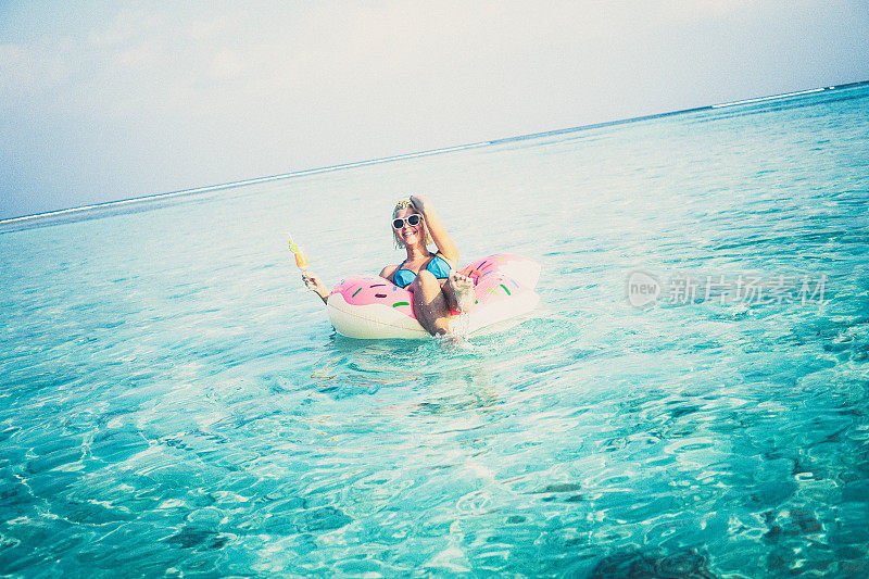 一个金发女人漂浮在马尔代夫的海洋里