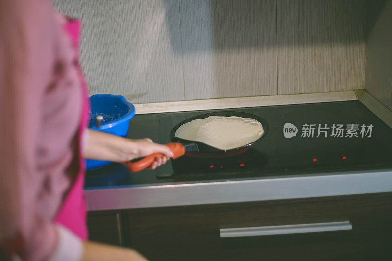 女孩倒了一勺面团做煎饼。在家做煎饼。