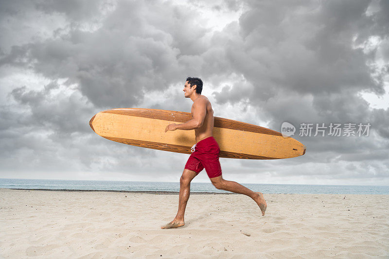 西班牙冲浪者与一个戏剧性的天空在海洋上奔跑