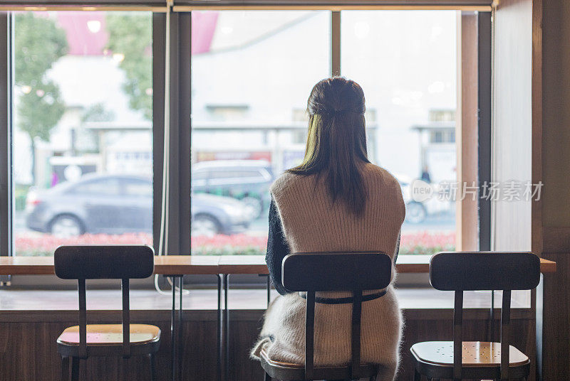 女人坐在咖啡馆的后视图