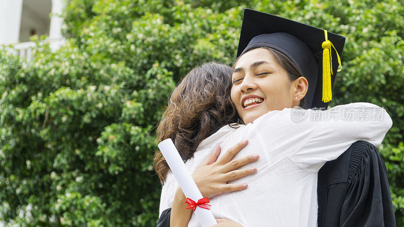 在祝贺仪式上，身着毕业礼服、头戴毕业帽的女同学拥抱家长。