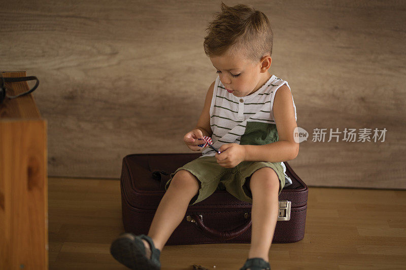 男孩(3-5)坐在手提箱上。