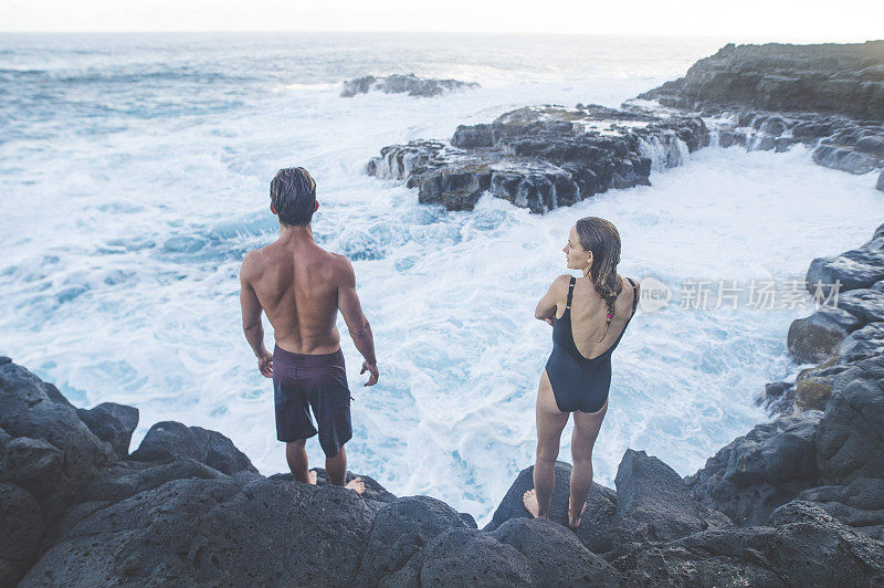 肌肉发达的男女穿着泳衣在夏威夷的悬崖上欣赏海浪