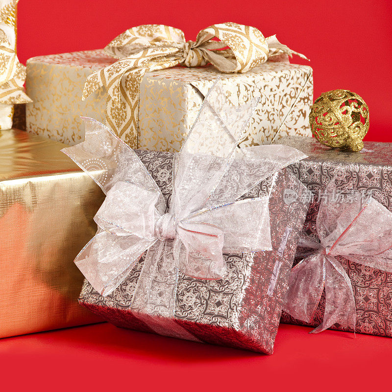 带着蝴蝶结和圣诞舞会的圣诞礼物。包裹在红色背景上