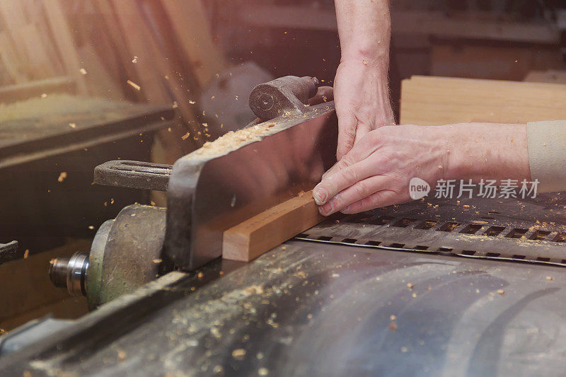 木匠在木工车间的木工机器上工作。男性手靠近。