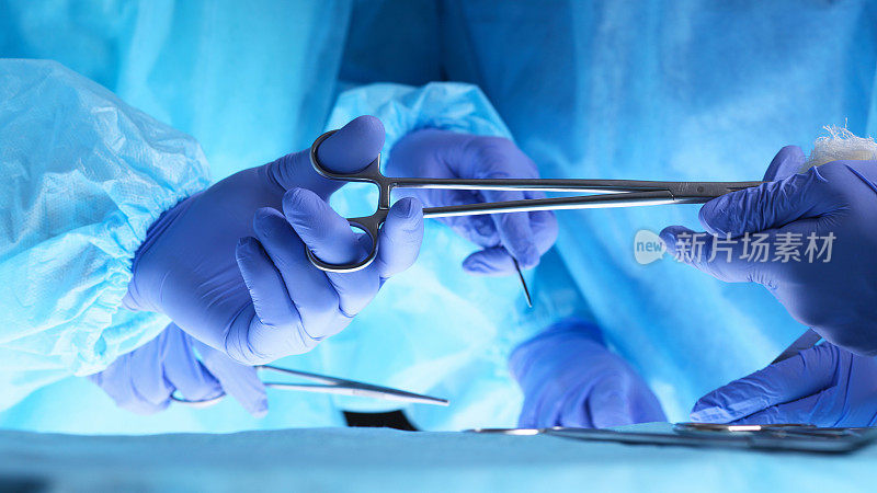 外科医生手握手术剪刀，传递手术设备，特写。保健和兽医概念